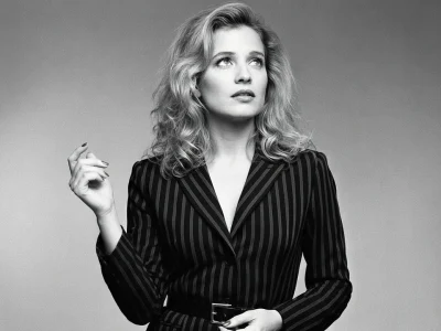 Pauline Lafont pose en blazer rayé sur ce portrait en noir et blanc la main levée vers le haut