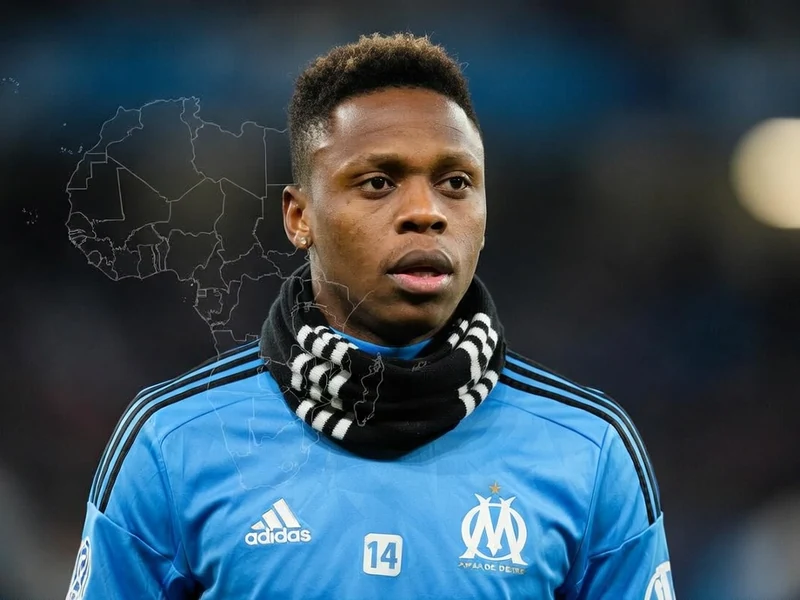 Njie apparaît en maillot bleu avec une écharpe autour du cou