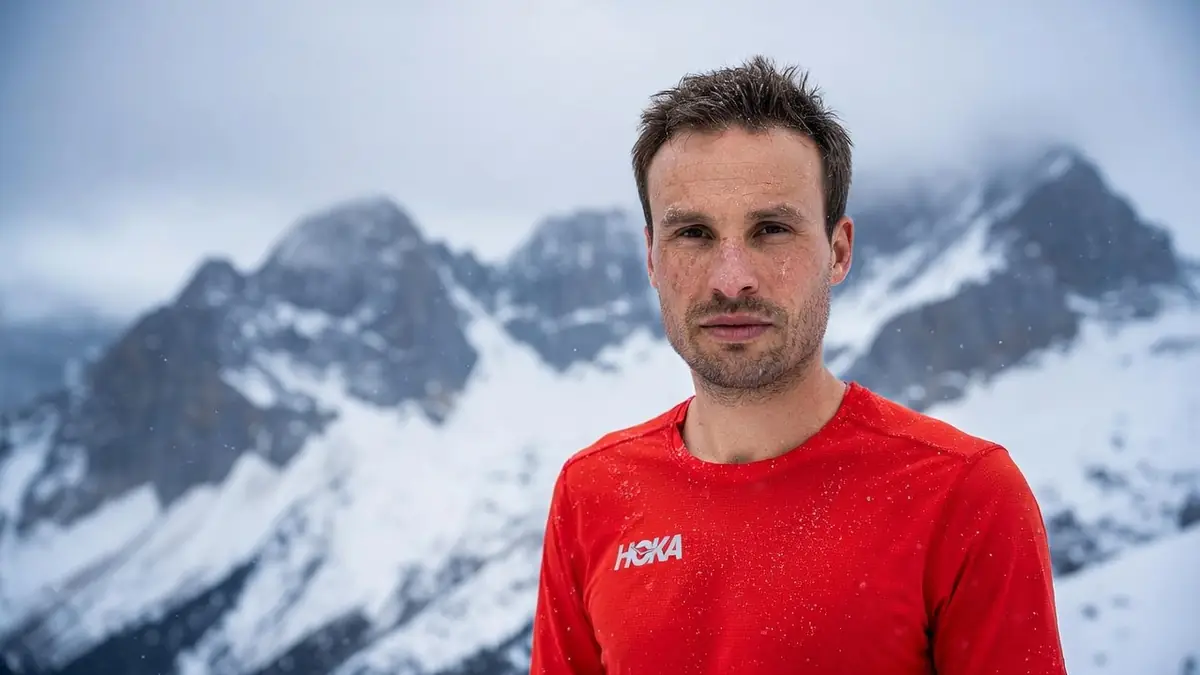 Thibaut Garrivier se tient en tenue rouge devant des montagnes enneigées