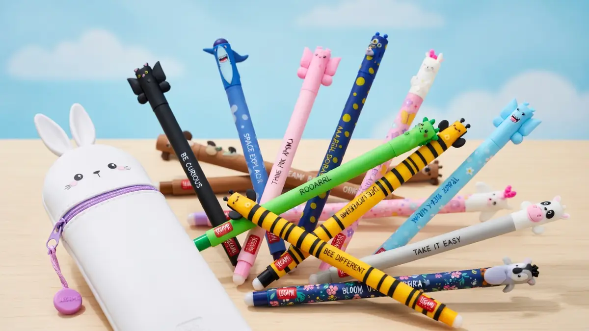 Des Legami stylo colorés avec des têtes d'animaux sont étalés devant une trousse lapin blanche