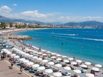 La plage du Carras animée de baigneurs et de parasols blancs sous un ciel bleu