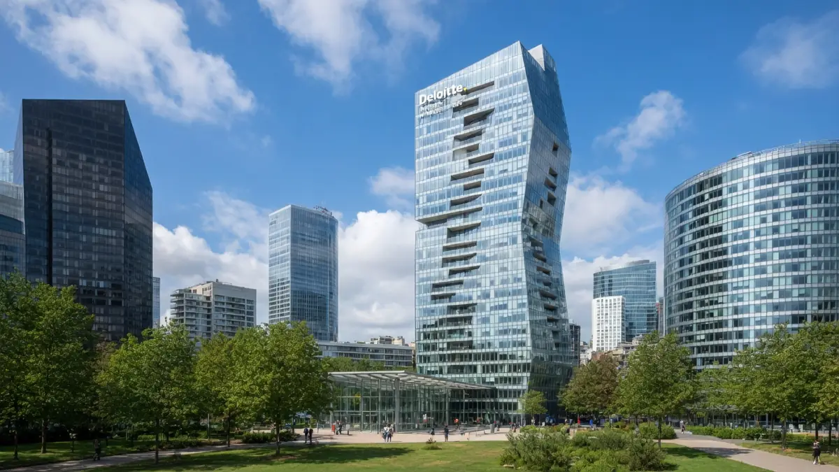La tour Majunga s'élève dans le ciel bleu entourée d'immeubles et d'arbres à La Défense