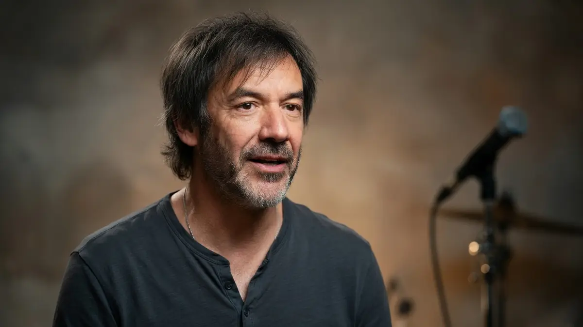 Thomas Vedebe en t-shirt noir avec micro sur fond texturé