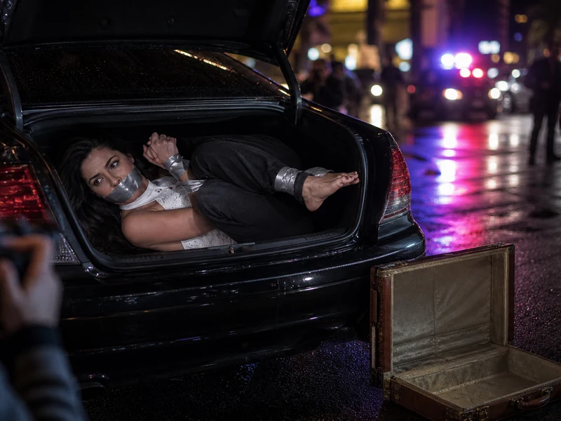 Scène nocturne de Las Vegas Heroes avec une femme retenue dans le coffre d'une berline.