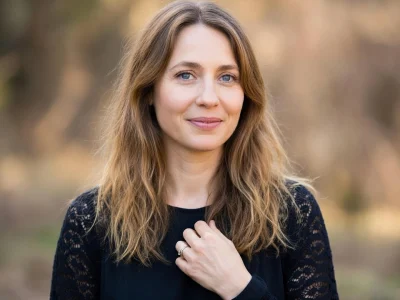 Laura Boujenah sourit légèrement avec la main sur la poitrine