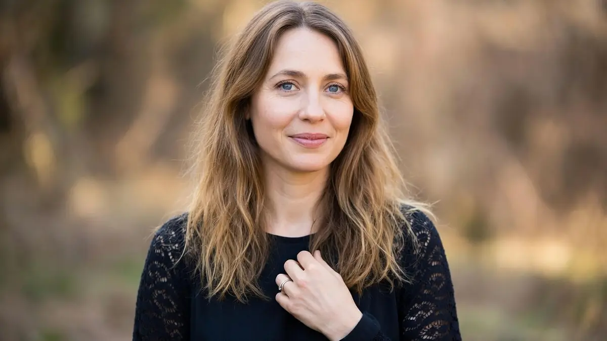 Laura Boujenah sourit légèrement avec la main sur la poitrine