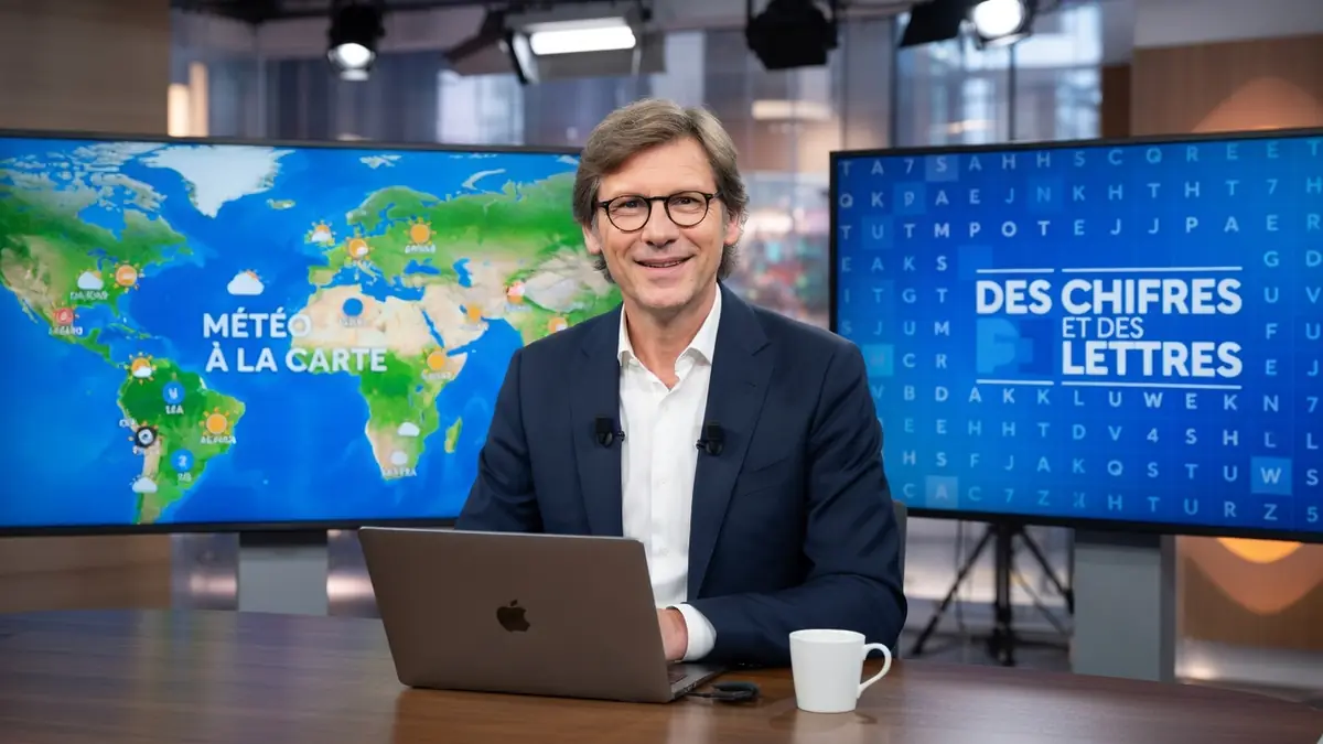 Laurent Romejko sourit à son bureau face à un ordinateur portable dans un studio de télévision