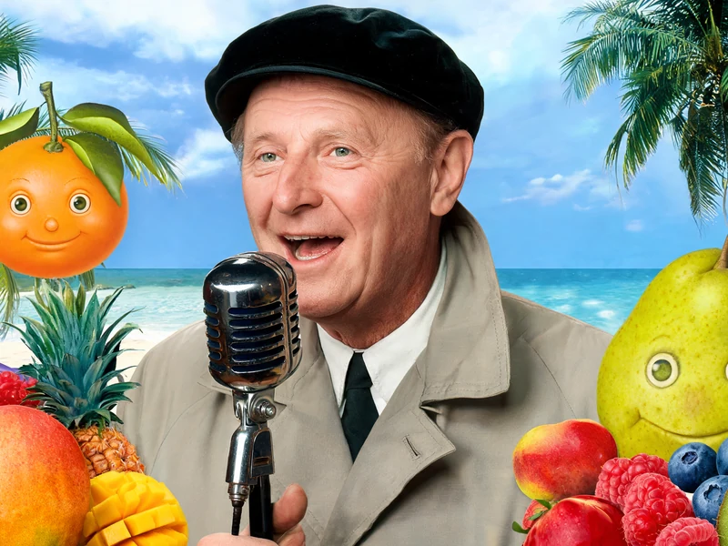 Bourvil chante au micro au milieu de fruits anthropomorphes sur une plage pour illustrer les salades de fruits Bourvil