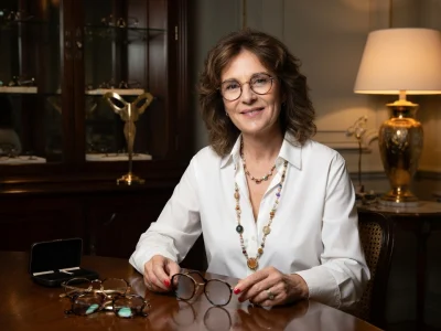 La créatrice Nathalie Blanc sourit en tenant une paire de lunettes dans un intérieur élégant