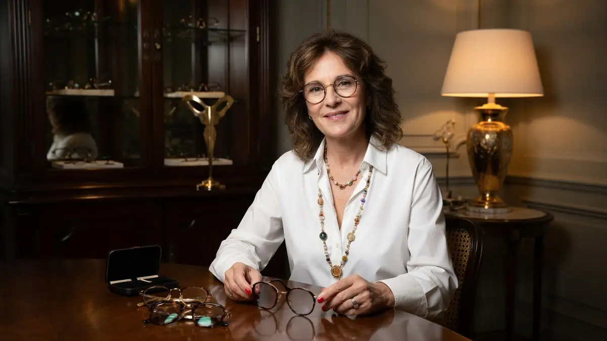 La créatrice Nathalie Blanc sourit en tenant une paire de lunettes dans un intérieur élégant