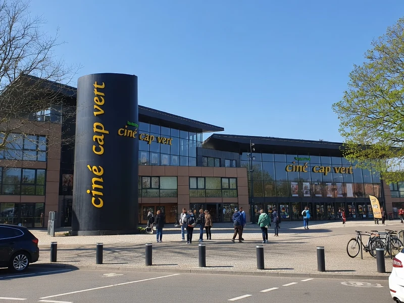 Façade moderne et parking du cinéma Cap-Vert sous un ciel bleu ensoleillé