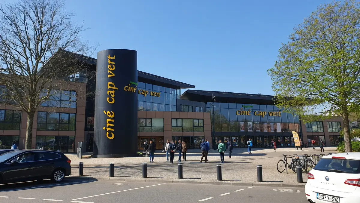 Façade moderne et parking du cinéma Cap-Vert sous un ciel bleu ensoleillé