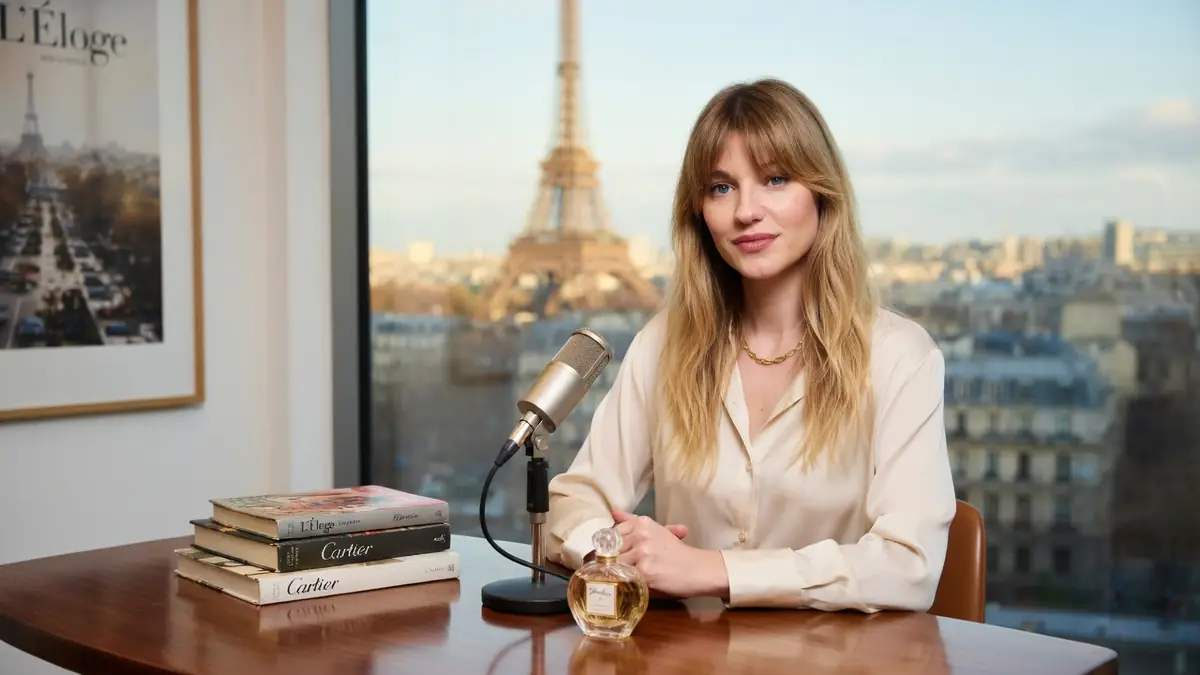 Constance Arnoult est assise à une table avec un micro devant la tour Eiffel