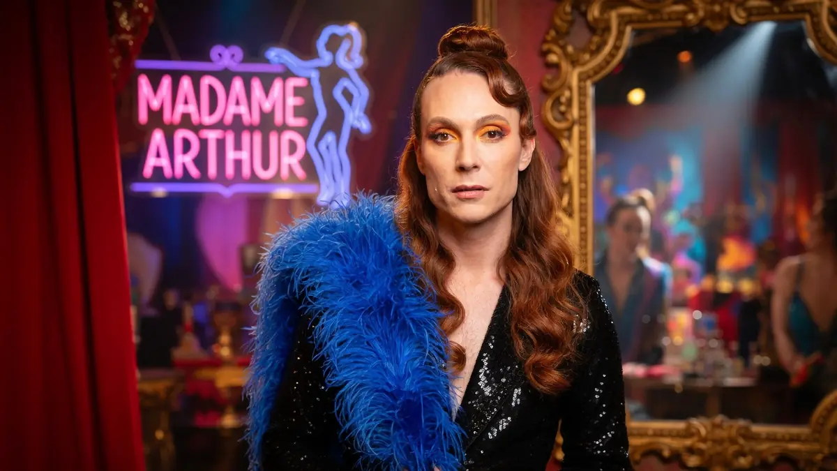 Romain Brau arbore un boa bleu et une veste à sequins dans un cadre de cabaret Romain Brau arbore un boa bleu et une veste à sequins dans un cadre de cabaret