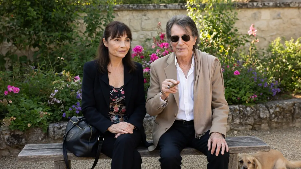 Sylvie Duval est assise sur un banc de jardin aux côtés de Jacques Dutronc