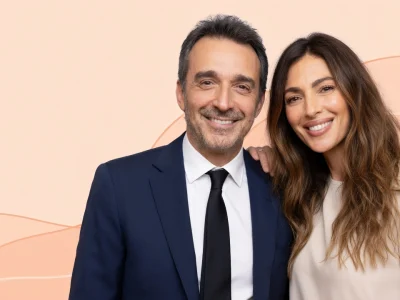 Clément Miserez pose souriant aux côtés d'une femme sur un fond beige aux lignes ondulées
