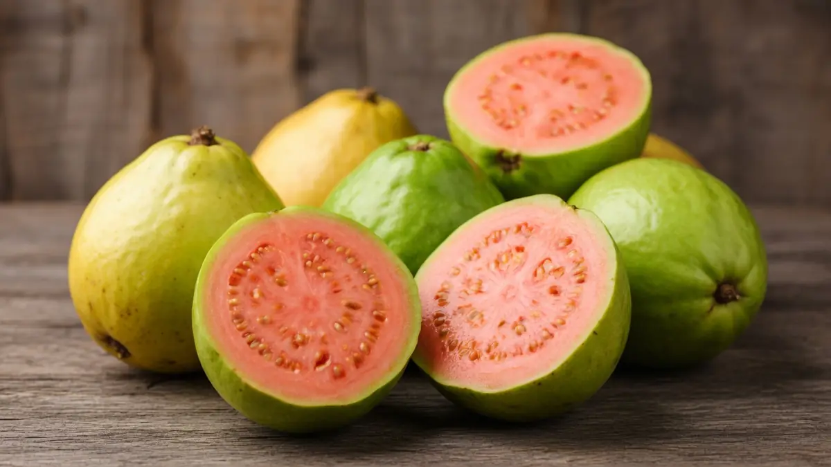 Des goyaves vertes et jaunes entières ou la goyave fruit coupée en deux sur une table
