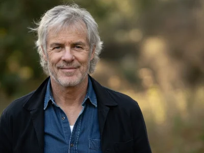 Olivier Pagès sourit légèrement en veste noire devant un fond de verdure flou