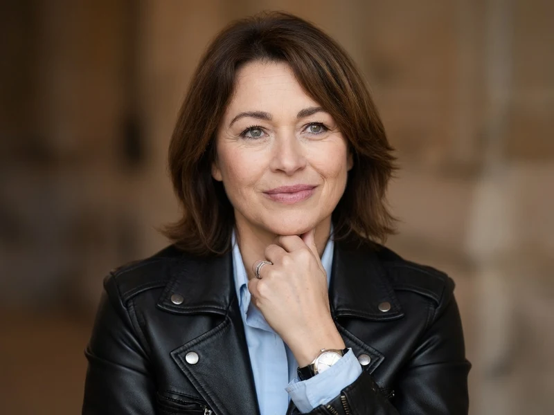 Virginie Caren pose avec sa main sur le menton dans un blouson en cuir noir