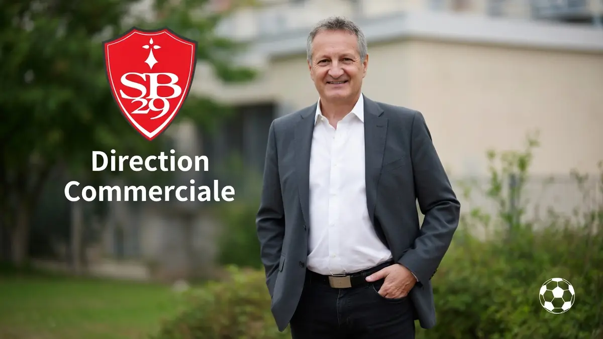 Pascal Robert se tient souriant en costume gris les mains dans les poches à l'extérieur