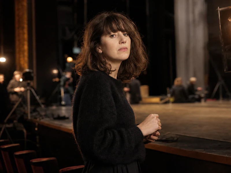 Manon Kneusé observe une scène de théâtre pendant une répétition.