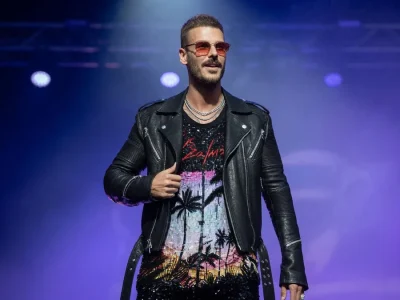 Matthieu Tota se tient sur scène en veste en cuir et lunettes de soleil sous lumières violettes