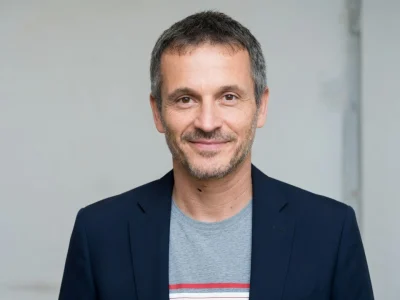 Nicolas Beaucaire sourit dans un portrait en buste avec veste bleue