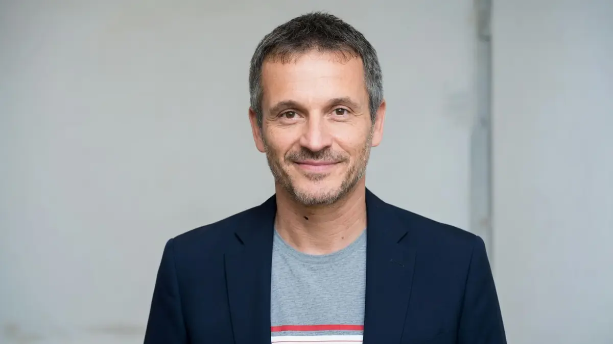 Nicolas Beaucaire sourit dans un portrait en buste avec veste bleue