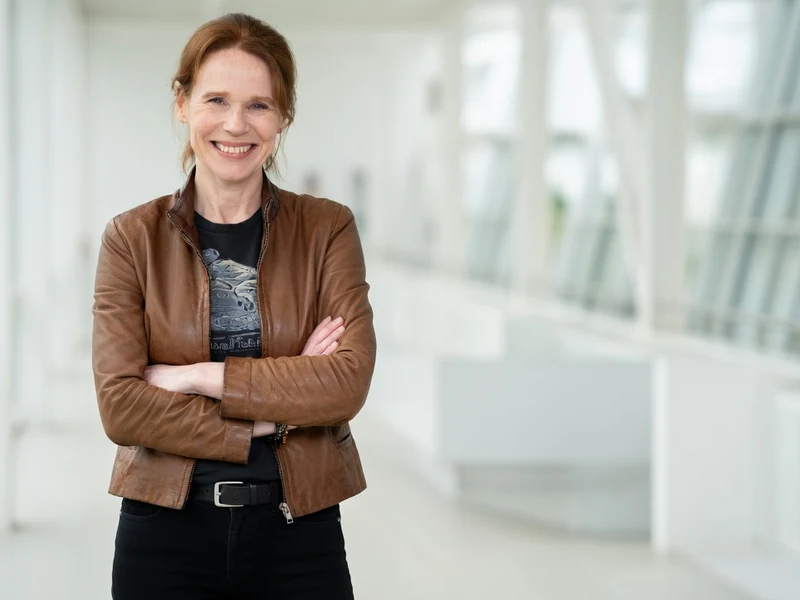Olivia Brunaux sourit avec les bras croisés dans un intérieur moderne et lumineux