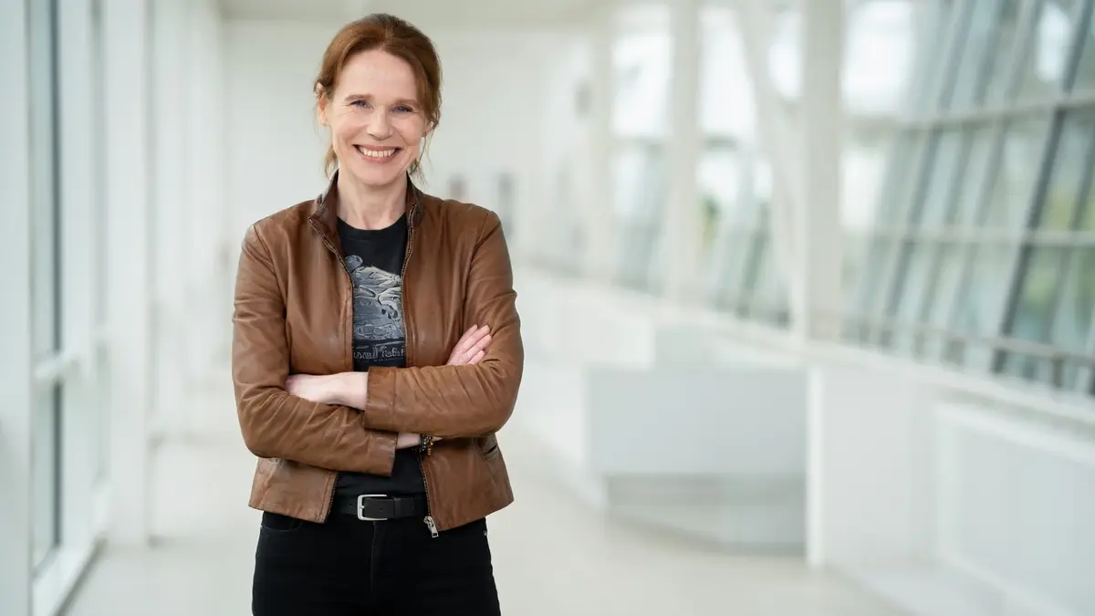 Olivia Brunaux sourit avec les bras croisés dans un intérieur moderne et lumineux