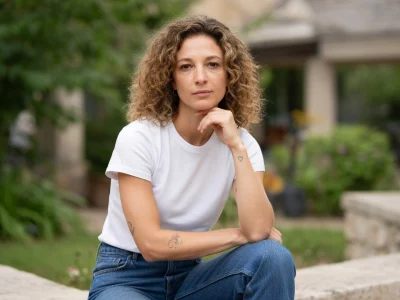 Portrait d'Olivia Courbis posant avec un t-shirt blanc dans un jardin extérieur