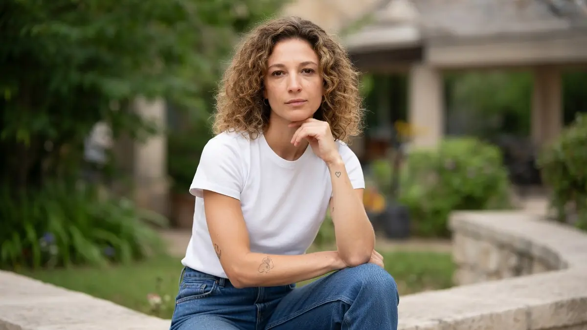 Portrait d'Olivia Courbis posant avec un t-shirt blanc dans un jardin extérieur