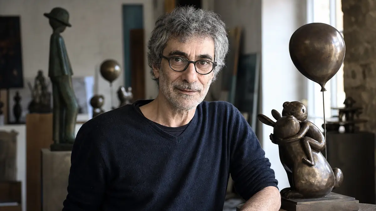 Philippe Berry pose dans son atelier auprès d'une sculpture en bronze inspirée de l'enfance.