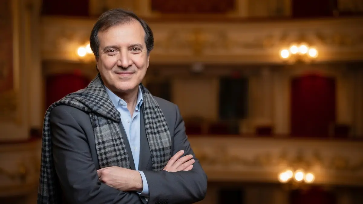 Philippe Uchan se tient les bras croisés avec une écharpe dans un théâtre