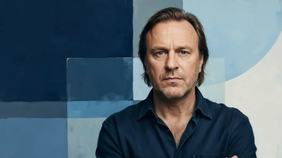 Pierre Bénézit les bras croisés sur un fond bleu abstrait