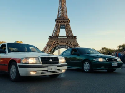 Un taxi et une voiture devant la tour Eiffel avec un policier pour streaming Taxi 2