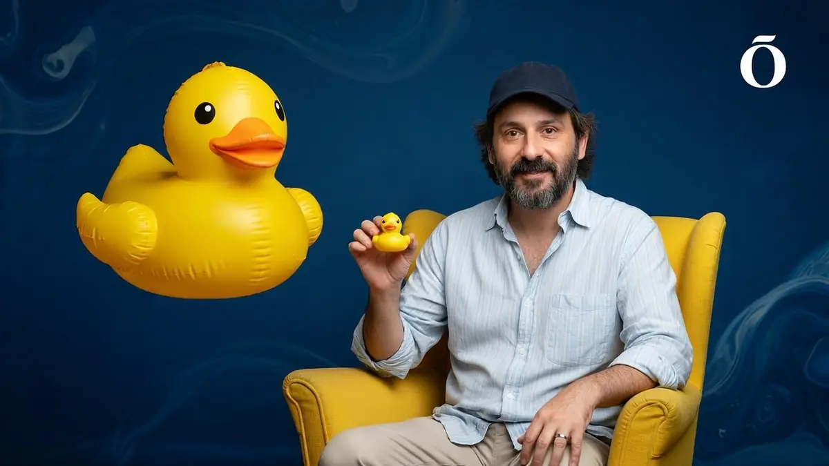 quentin dupieu est assis dans un fauteuil jaune en tenant un petit canard jaune à côté d'un grand canard en plastique