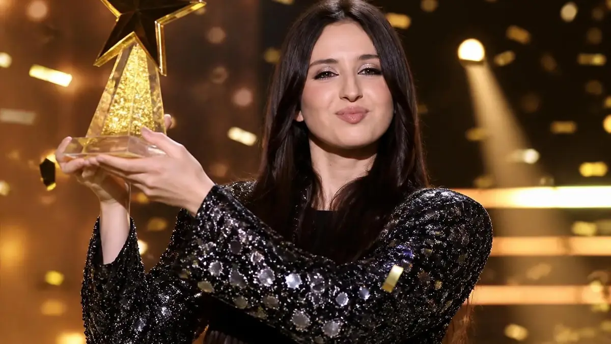 Ambre soulève son trophée en tant que personne qui a gagner la star ac 2025 sous une pluie de confettis dorés