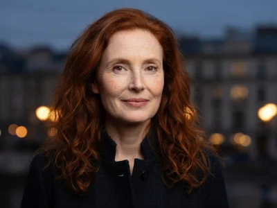 Portrait de l'actrice Rachel Lascar avec ses cheveux roux devant un fond urbain flou en soirée