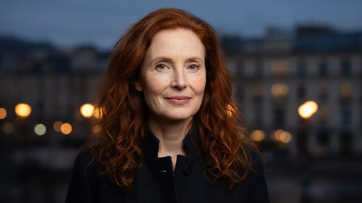 Portrait de l'actrice Rachel Lascar avec ses cheveux roux devant un fond urbain flou en soirée