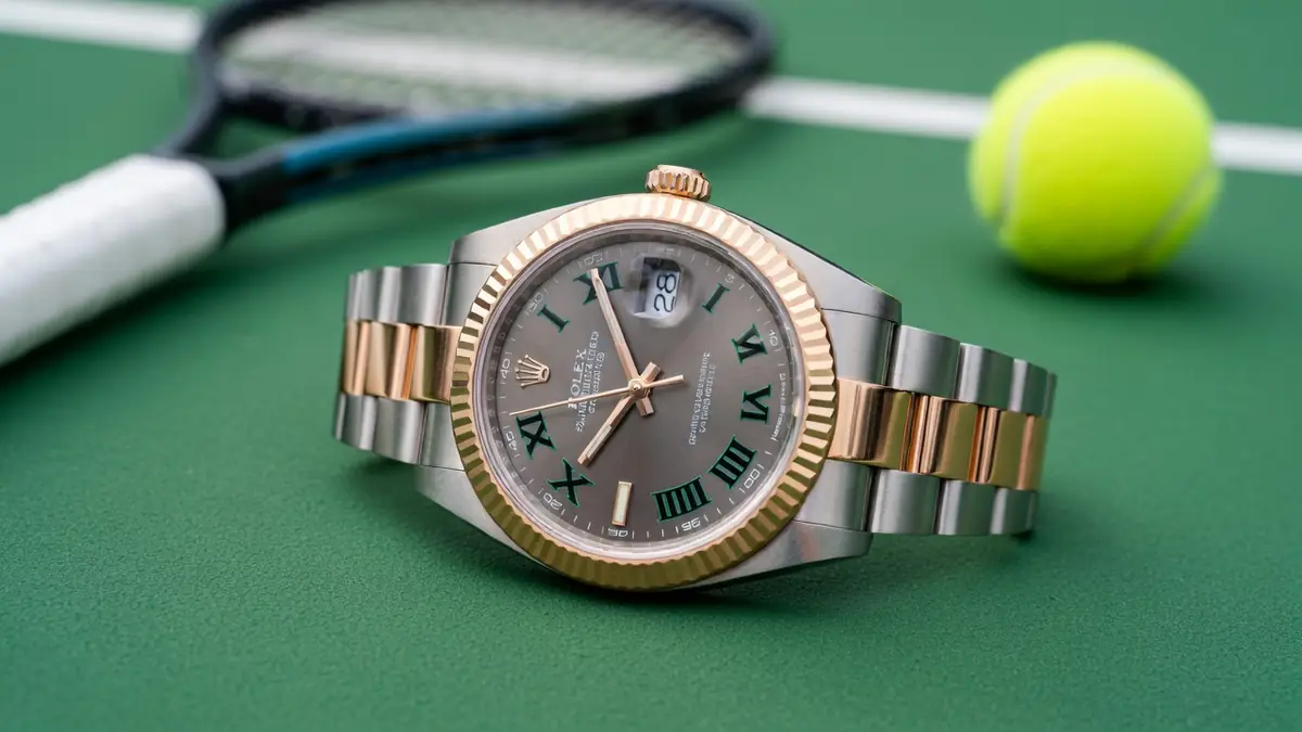 Montre Rolex Wimbledon posée sur un court de tennis avec une raquette et une balle en arrière-plan