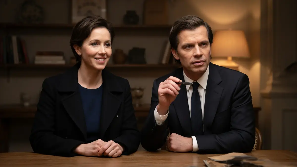 Simon Hubert est assis à une table en bois aux côtés d'une femme souriante dans une pièce chaleureuse