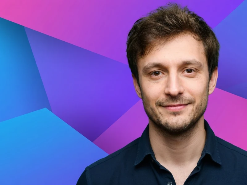 Tom Hudson pose devant un fond aux formes géométriques colorées