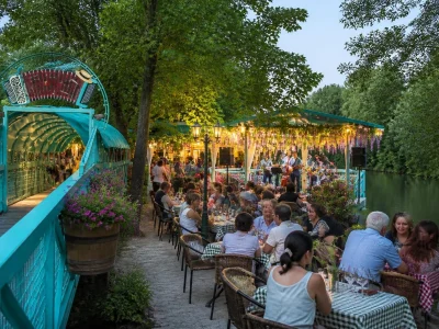 Terrasse animée et verdoyante au bord de l'eau à la guinguette Île du Martin-Pêcheur