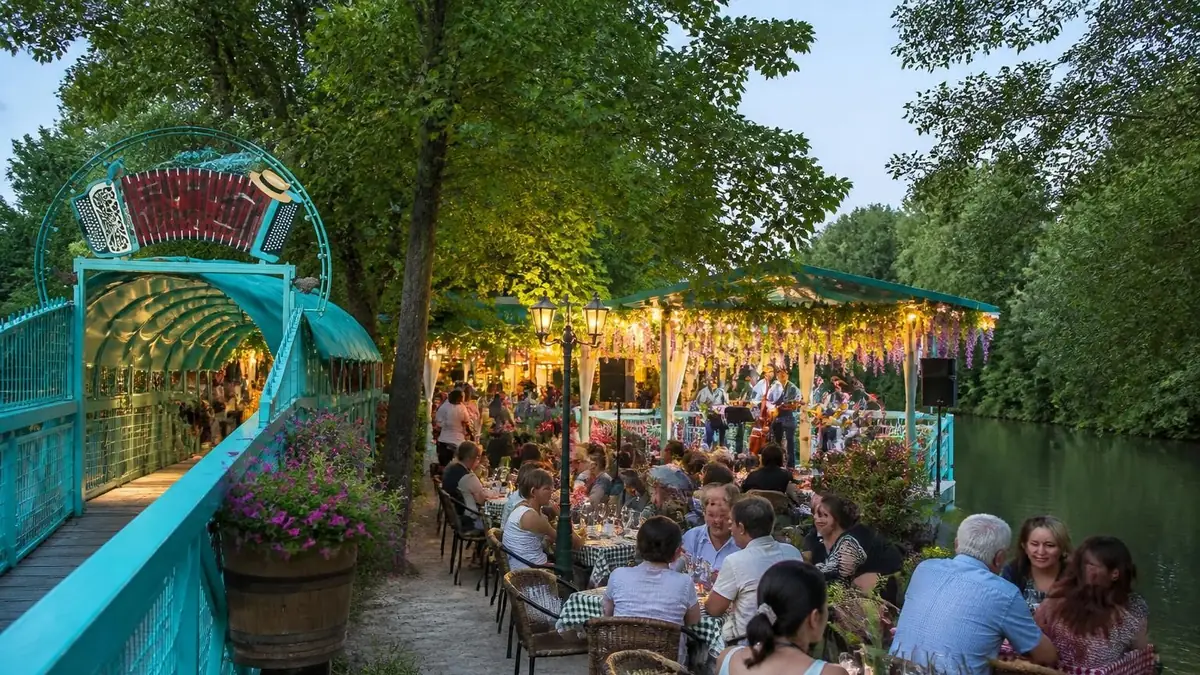 Terrasse animée et verdoyante au bord de l'eau à la guinguette Île du Martin-Pêcheur