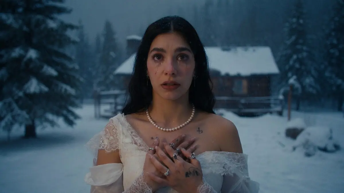 Une femme en robe blanche dans un paysage enneigé semble avoir un très mauvais pressentiment