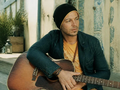 Christophe Maé pose avec sa guitare acoustique, un moment où on s'attache Christophe Maé par sa simplicité