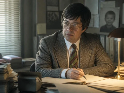 L'acteur incarnant Lambert Jean Michel travaillant à son bureau sur un dossier judiciaire
