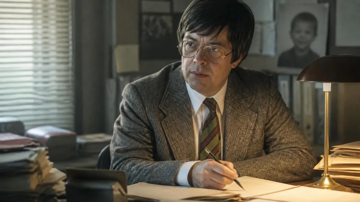 L'acteur incarnant Lambert Jean Michel travaillant à son bureau sur un dossier judiciaire