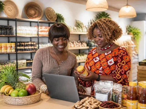 Deux femmes souriantes travaillent sur un ordinateur au sein d'une épicerie africaine moderne et bien achalandée